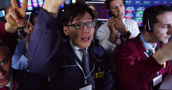  Diverse group of stockmarket traders frantically buying and selling on the trading floor. Shot on RED Epic.