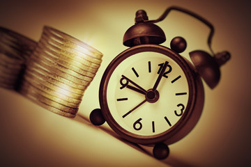 time is money concept. old clock and stack of euro coins.