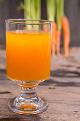 Fresh-squeezed carrot juice on wooden background