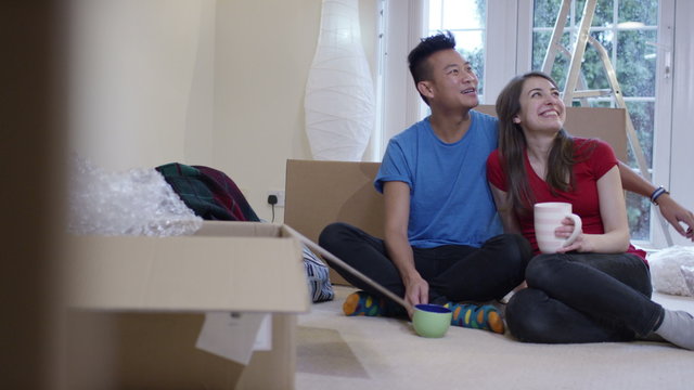  Young couple take a coffee break from unpacking boxes in new home