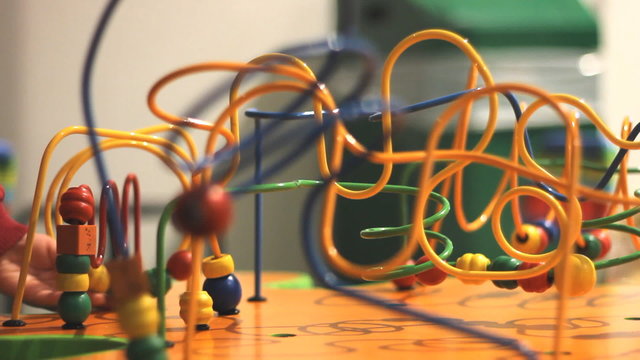 Children hand playing colorful bead roller coaster