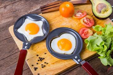 Pan of fried eggs, with .vegetable on a wooden table surface