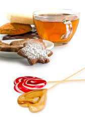 Isolated image of cup of tea, candy and cookies on white background closeup