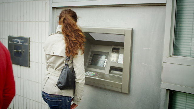  suspicious woman taking cash from an ATM machine