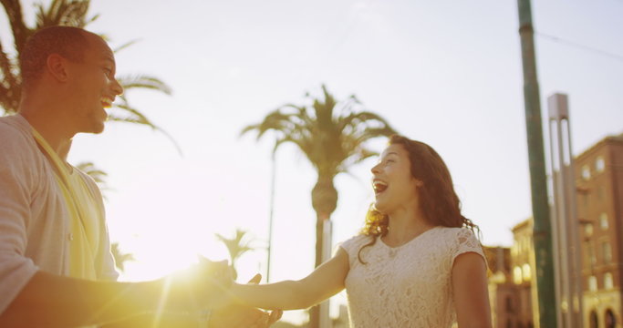  Happy romantic couple outdoors in the city, dancing as the sun begins to set. 