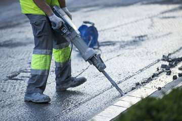 Builder worker with pneumatic hammer drill equipment breaking as