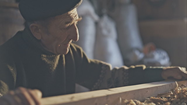 The hard manual labor Old farmer carpenter in the workshop day. Sunlight