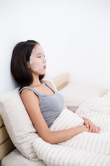 Obraz na płótnie Canvas Asian Woman lay down and doing facial mask