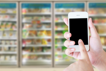 Female hand holding mobile smart phone on Supermarket blur backg