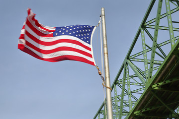 Astoria Bridge and Flag horizontal, Oregon. An American flag flies beside the Astoria Megler bridge which connects Oregon and Washington over the Columbia River.
