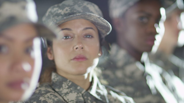  Close up on faces of mixed ethnicity female soldiers standing to attention. 