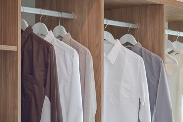 Classic color shirts hanging in wooden wardrobe