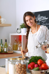 Cooking woman in kitchen with wooden spoon