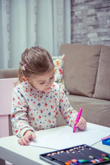 Little girl is painting and drawing with crayons.