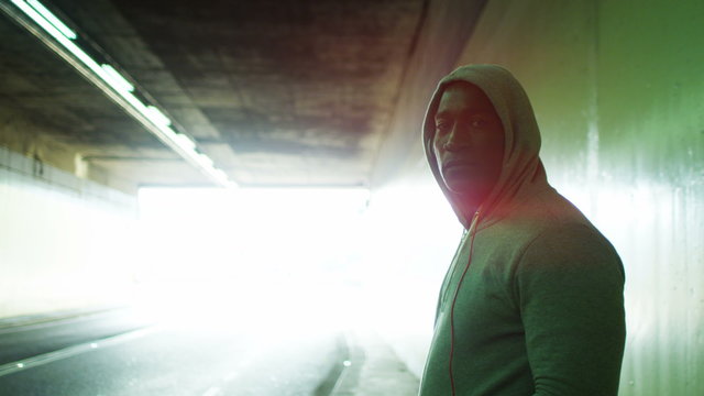  Portrait of athletic black male in a hooded sweatshirt, in urban environment. Could be an athlete in training or a suspicious character.