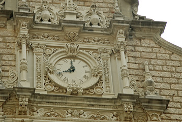 Obraz premium MONTSERRAT, SPAIN - AUGUST 28, 2012: Benedictine abbey Santa Maria de Montserrat in Monistrol de Montserrat, Spain. Details of the church clock