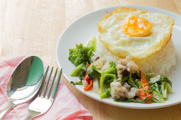Hot basil octopus with fried egg on wood table.