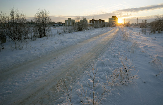 Winter road leading to the house at sunset.