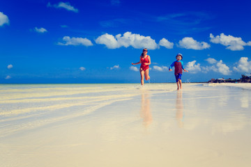little boy and mother running on beach