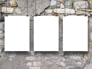 Three hanged paper sheet frames with clips on grey damaged brick wall background