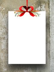 Single empty rectangular paper sheet frame with Xmas ribbon decoration on brown scratched plastered wall background