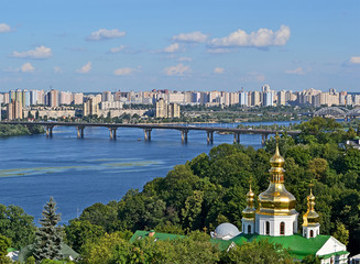 Fototapeta na wymiar Kiev summer landscape with Kyiv Pechersk Lavra cupola, Dnieper river and bridge in sunny day. and blue sky with white clouds. 
