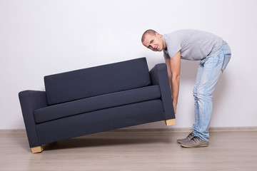 young man lifting up sofa or couch