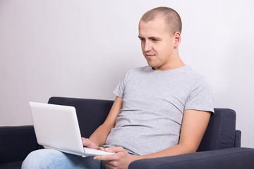 young handsome man sitting on sofa with computer