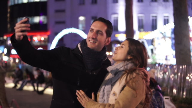 EDITORIAL  Happy romantic couple pose to take a selfie at Christmas fair. Shot on RED Epic.