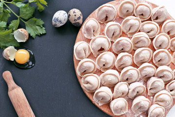 Raw ravioli  with parsley, eggs on wooden desk and black stone board 