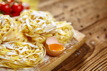 Raw homemade pasta and ingredients for pasta on wooden backgroun