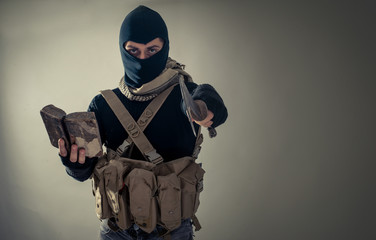 Portrait of man with book and weapon standing against gray background