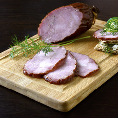 Traditional smoked sausage with dill, sandwich and vegetables on a wooden cutting board