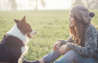 Young woman playing with her border collie dog - obrazy, fototapety, plakaty