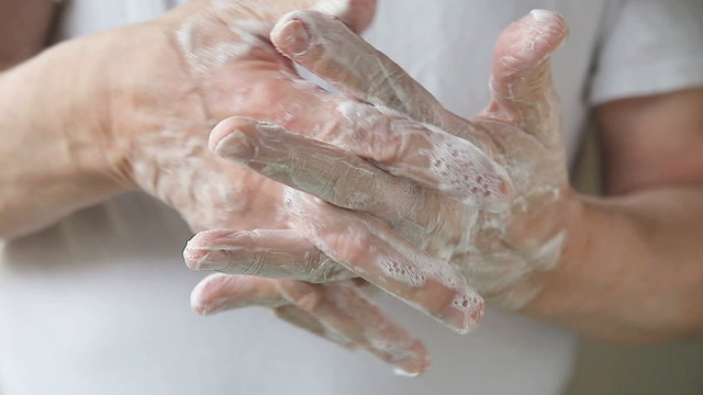 A man works soapy lather into his hands.