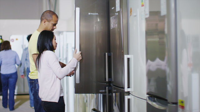 Couple shopping in a shop selling fridges and washing machines dishwashers and kitchen products. 
