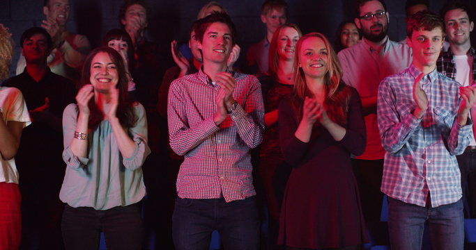  Young theatre audience give a standing ovation to the performers on stage