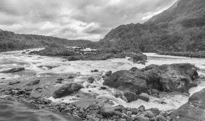 Mountain fast flowing river stream of water in the rocks with cloudy sky