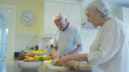 Affectionate senior couple preparing a meal together in the kitchen at home - Powered by Adobe