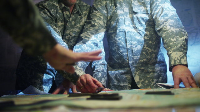  Military officers in army bunker, looking at map & discussing battle strategy