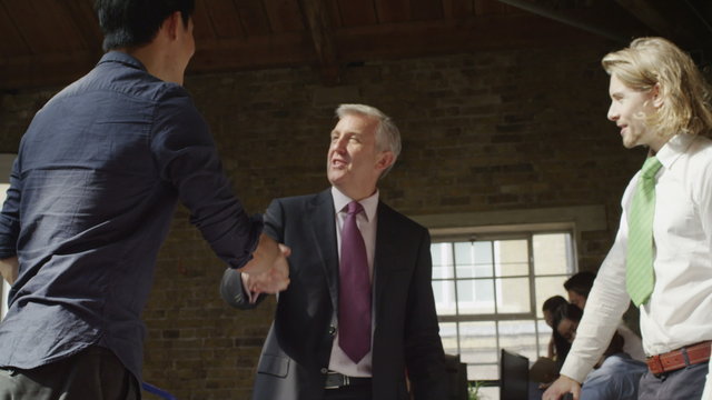  businessmen in modern office shake hands at the end of a meeting