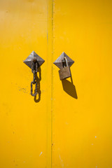 Closed yellow doors with lock and shadow of lock
