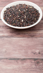 Black glutinous rice in wooden bowl over wooden backgound