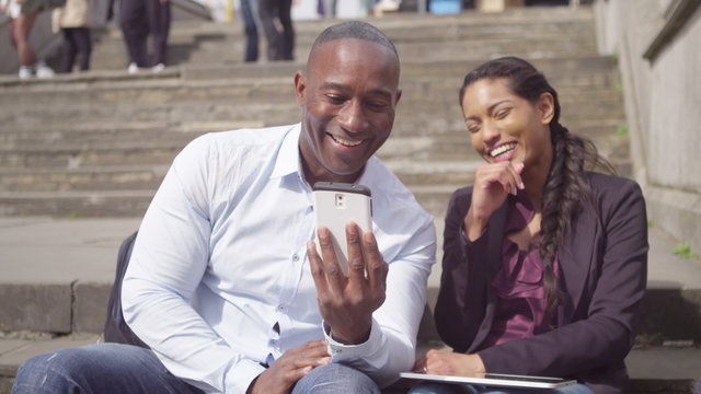  Happy mixed ethnicity couple using technology in the city.