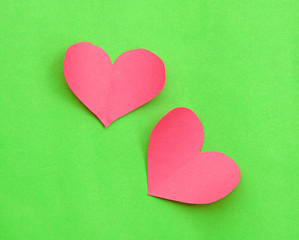 Pink paper hearts on green background