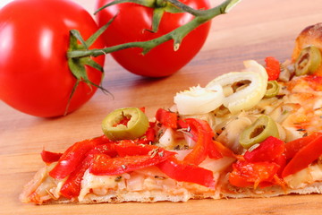 Slice of vegetarian pizza and tomatoes on wooden surface