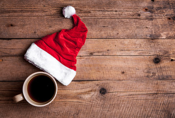 Cup of coffee and Santas hat on a wooden background, celebration - 97978494