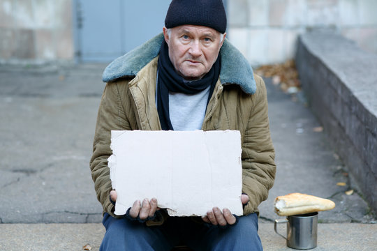 Homeless man holding a cardboard sign.