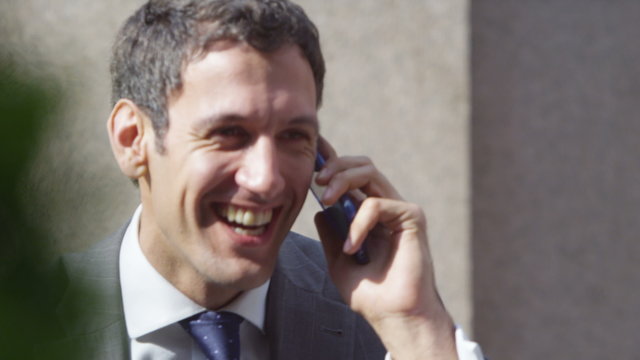 confident businessman closes deal on smart phone outside office building.