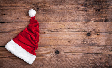 Obraz na płótnie Canvas Santa red hat on wooden background, holiday Christmas